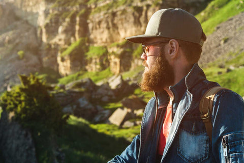 Bearded Man with Cap and Backpack Hiking in the Mountains